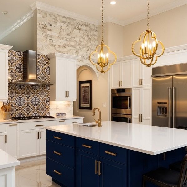Modern kitchen with navy island, white cabinets, gold pendant lights, and patterned tile backsplash in Rockville