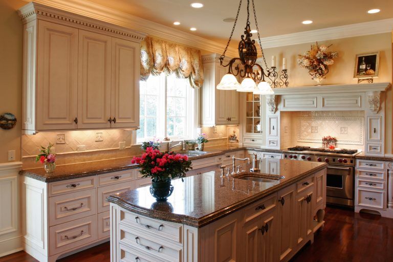 Elegant kitchen with cream cabinets, granite island, pendant lights, and flowers on the counter in Rockville
