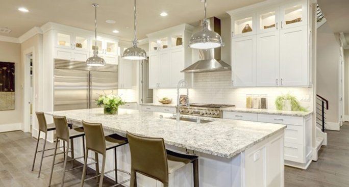 Bright modern kitchen with white cabinets, marble island, and stainless steel pendant lights in Brookeville