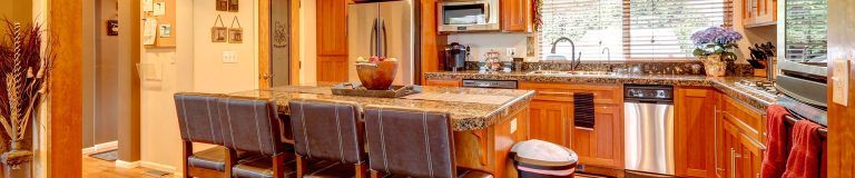 Cozy wooden kitchen with dining table, chairs, and warm orange cabinetry and decor in Rockville