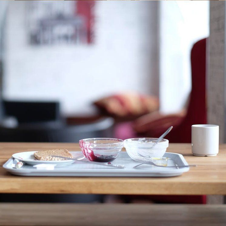 Tray with three small bowls and a cup on a wooden table in a blurred café setting in Rockville