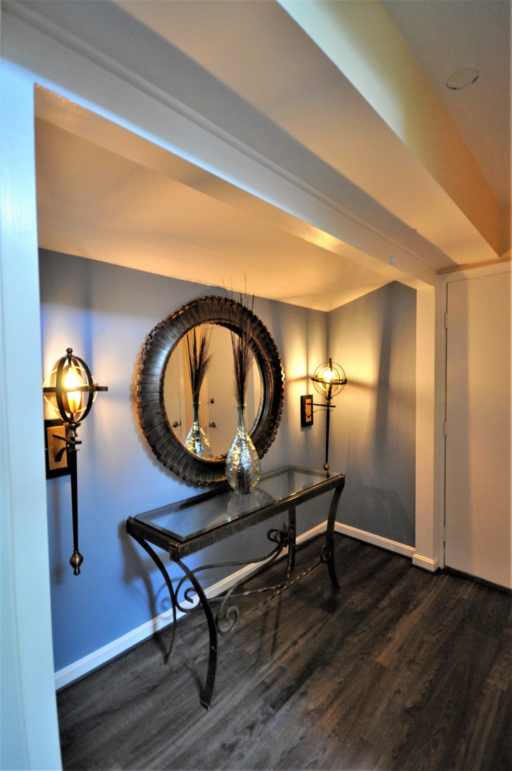Elegant hallway with blue walls, exposed beams, a decorative mirror, console table, and wall sconces in Rockville