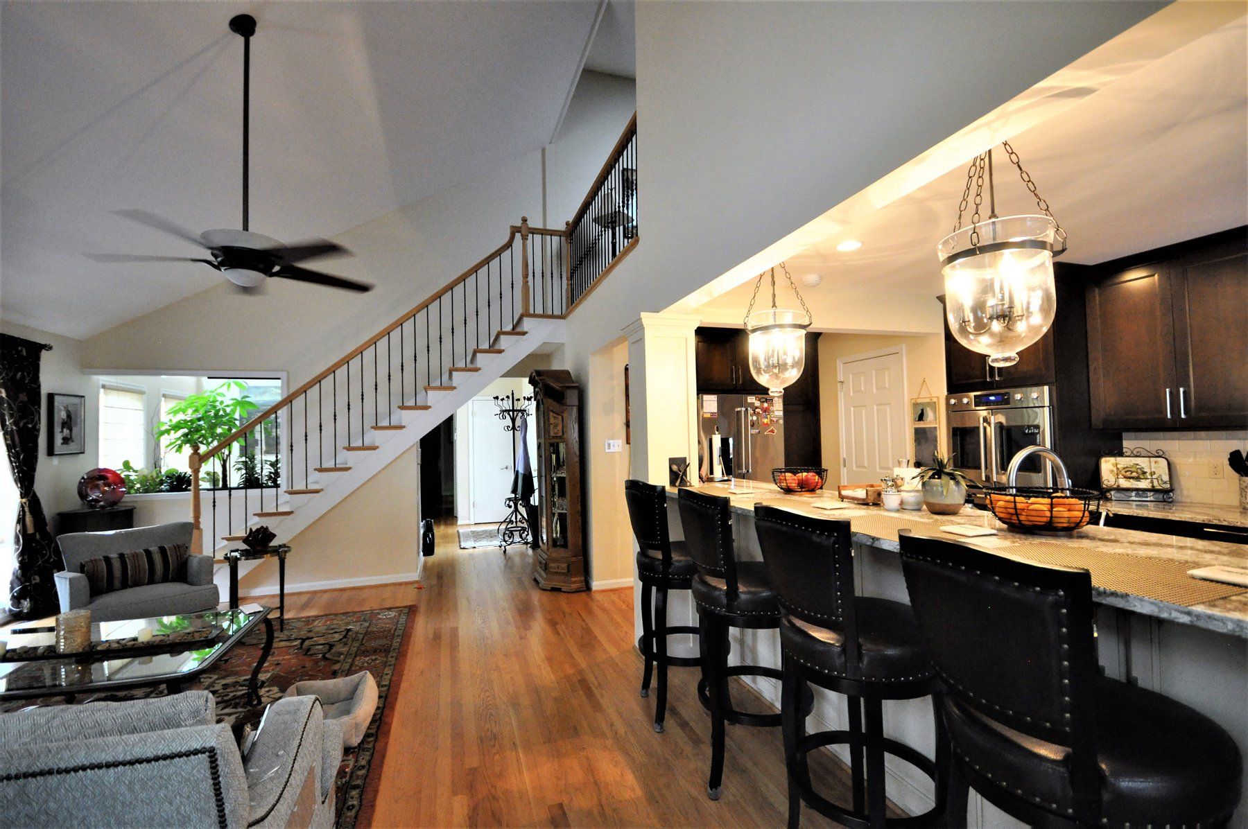 Open-plan home interior with staircase, living area, and kitchen with dark bar stools and pendant lights in Rockville