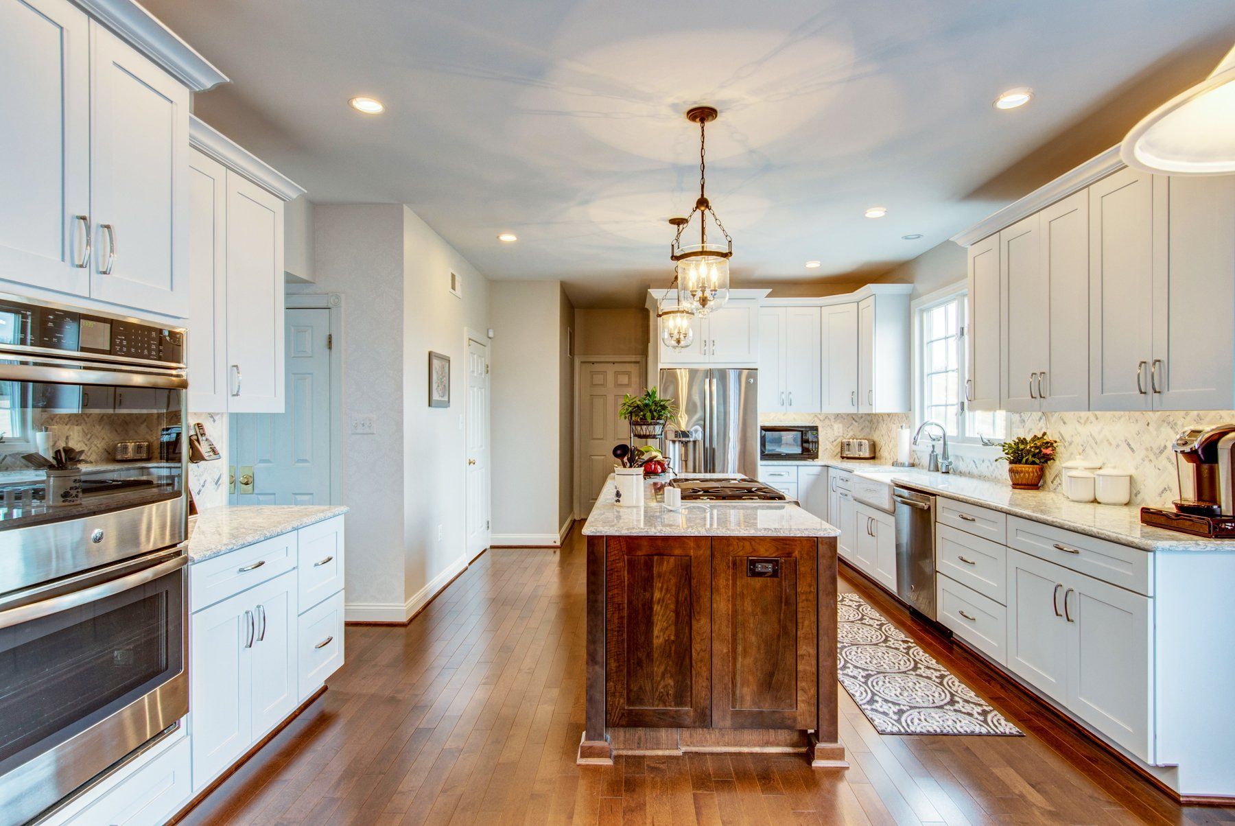 Bright modern kitchen with white cabinets, stainless appliances, and a wooden island on hardwood floors in Bethesda