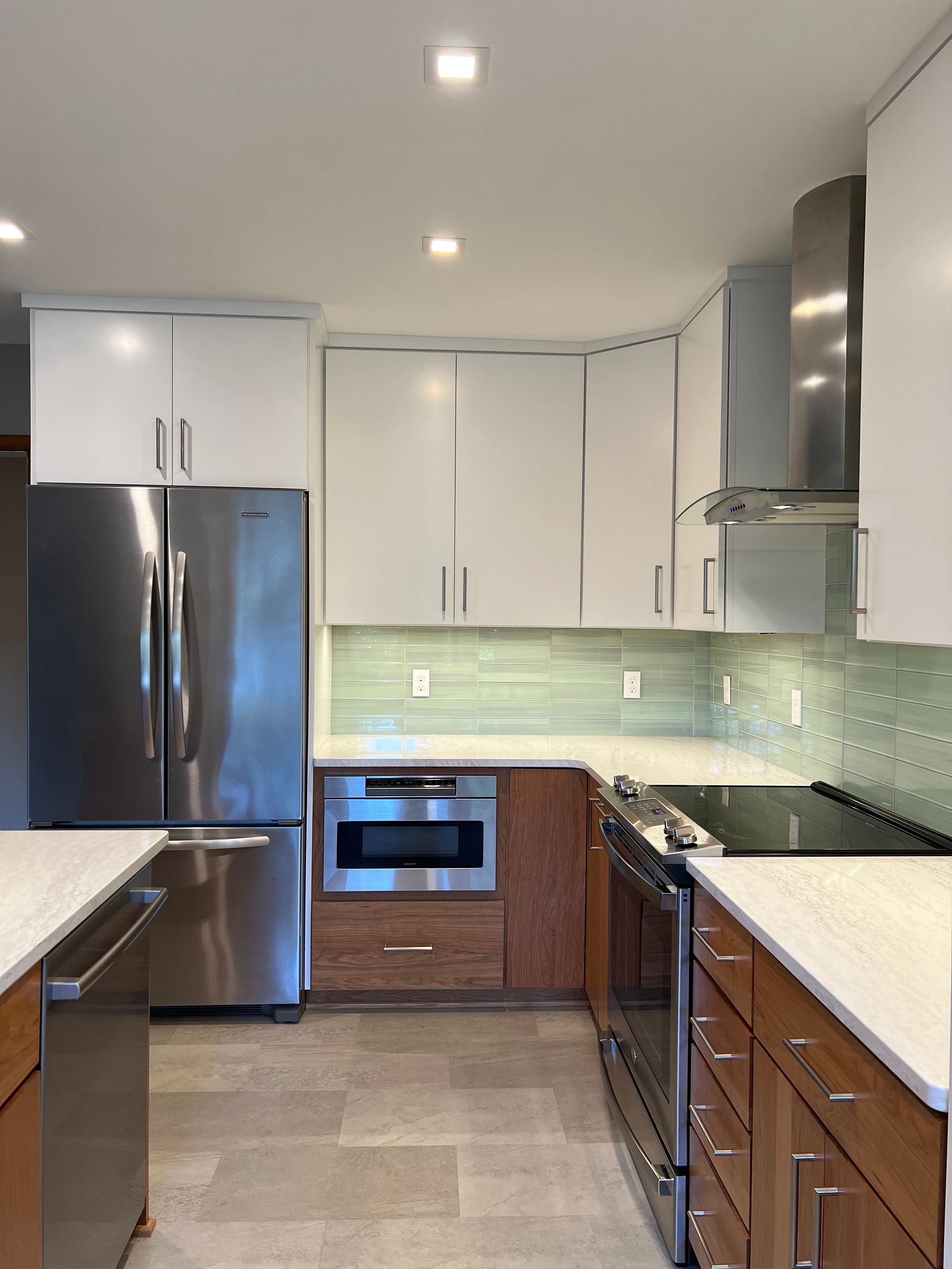Modern kitchen with stainless steel appliances, white cabinets, and wood lower cabinets in Rockville