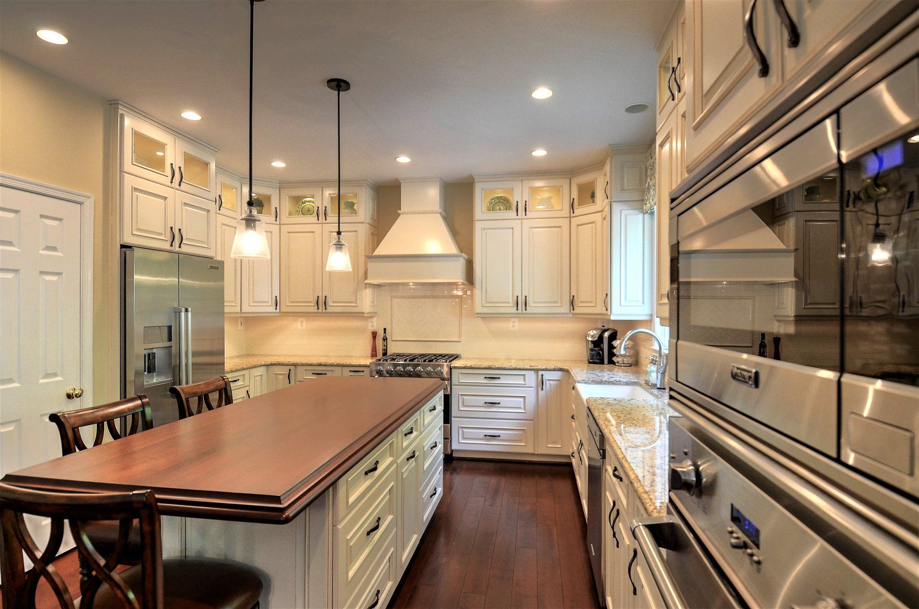 Modern kitchen with island, white cabinets, hardwood floors, and stainless steel appliances in Rockville
