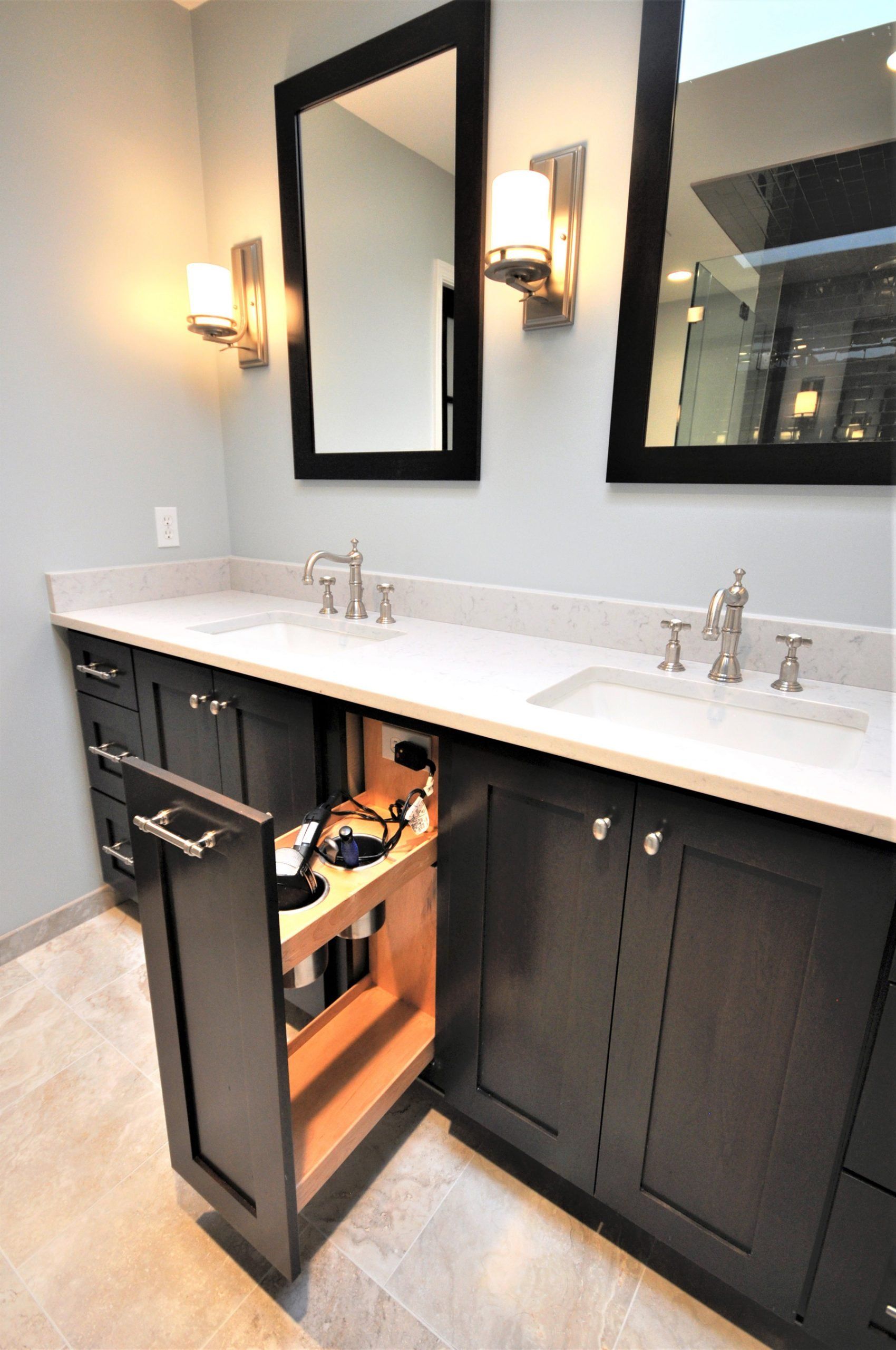 Modern bathroom vanity with double sinks, black cabinets, mirrors, and an open under-sink drawer with lighting in Rockville
