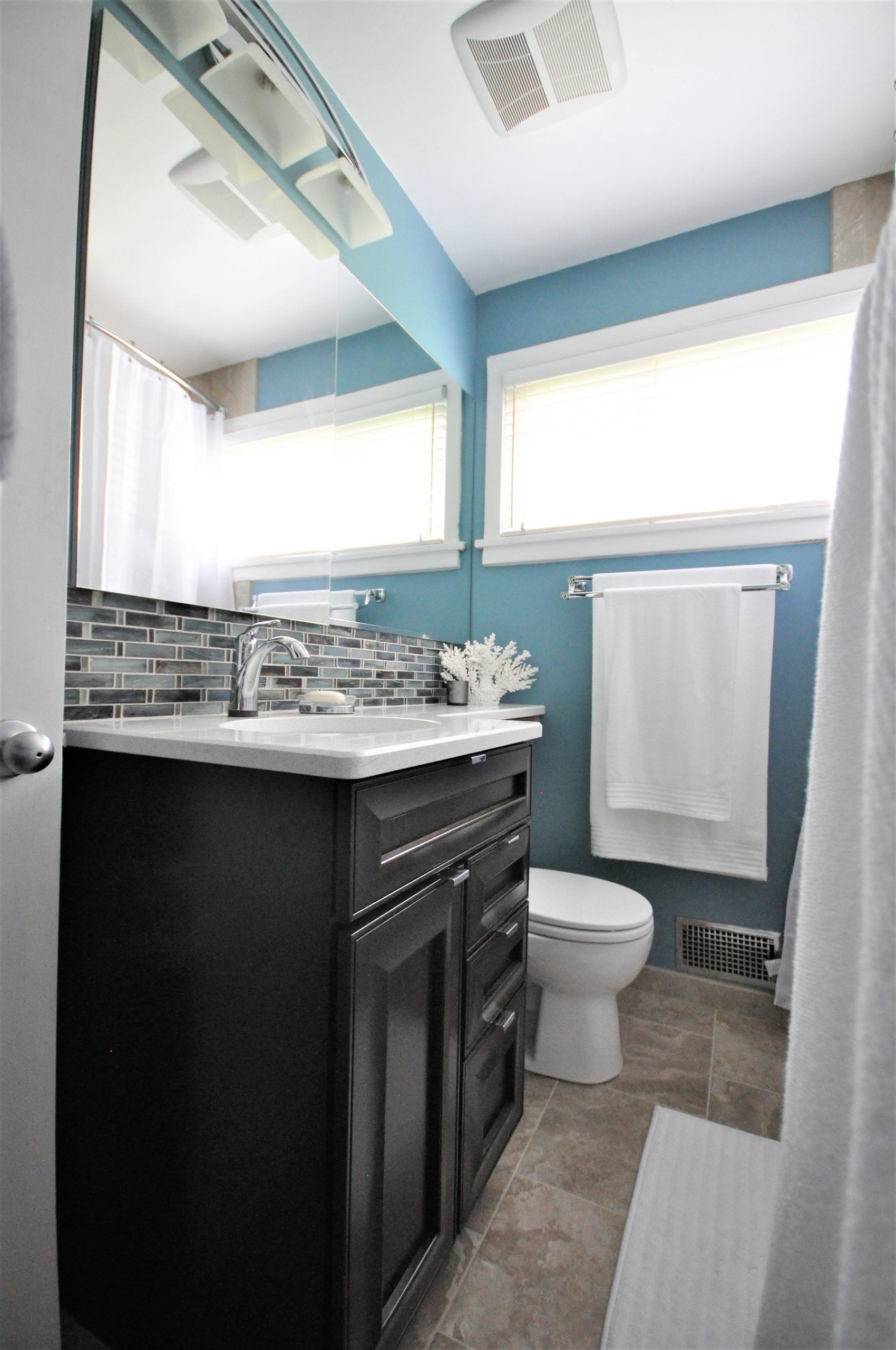 Small bathroom with blue walls, black vanity, white toilet, and tiled floor in Rockville