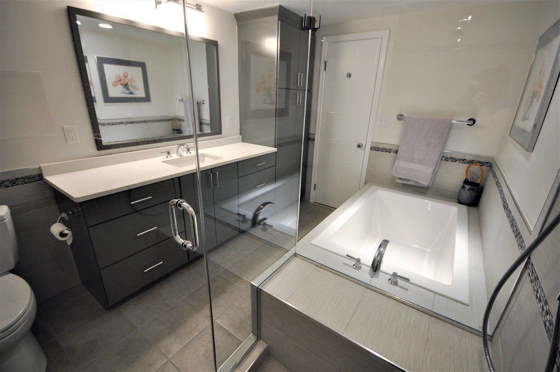 Modern bathroom with double vanity, glass shower, and large soaking tub in Rockville
