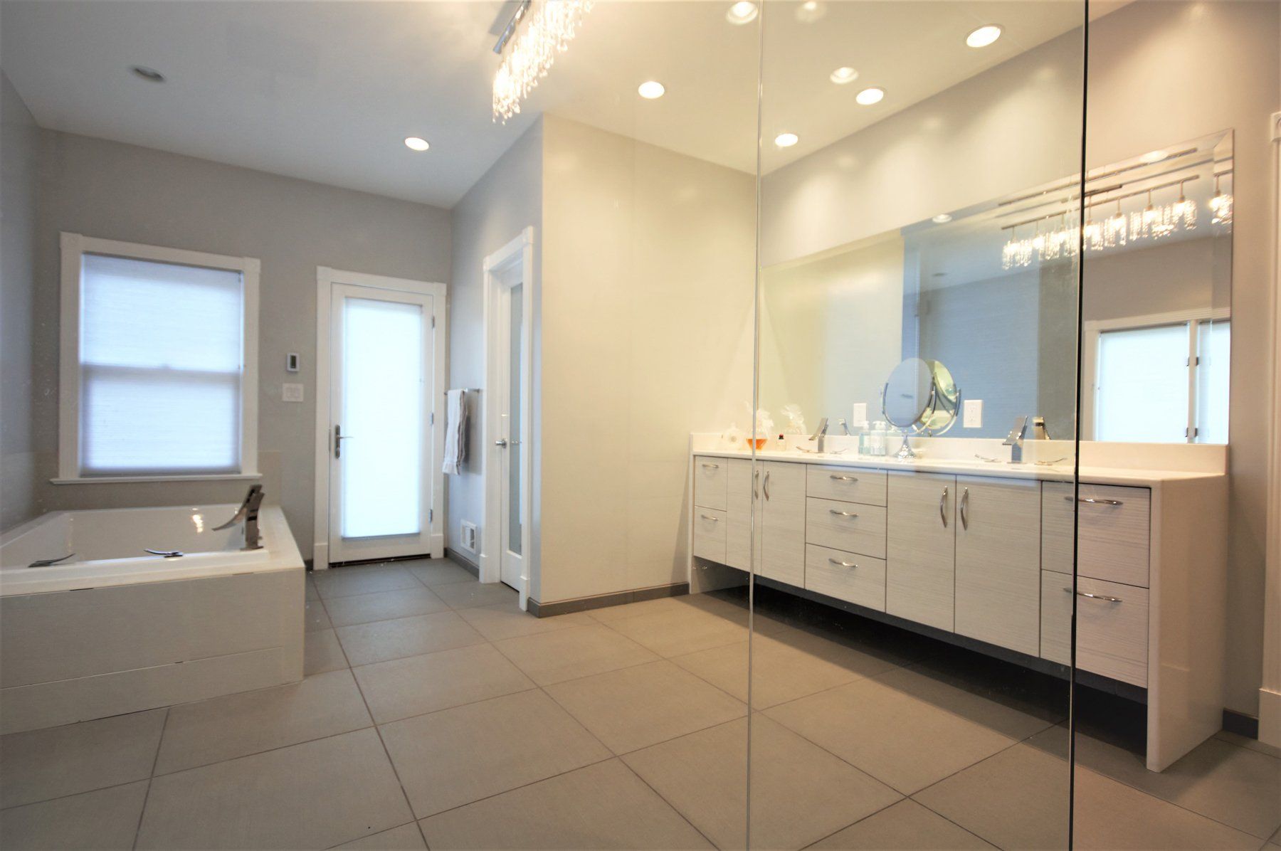 Spacious modern bathroom with double vanity, large mirror, bathtub, and tiled floor in Rockville