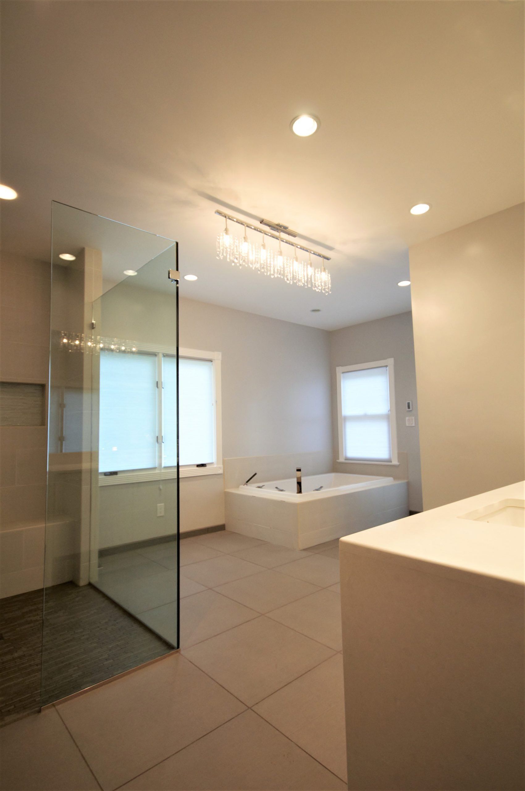 Modern bathroom with glass shower, bathtub, double sink, and beige tile flooring in Gaithersburg