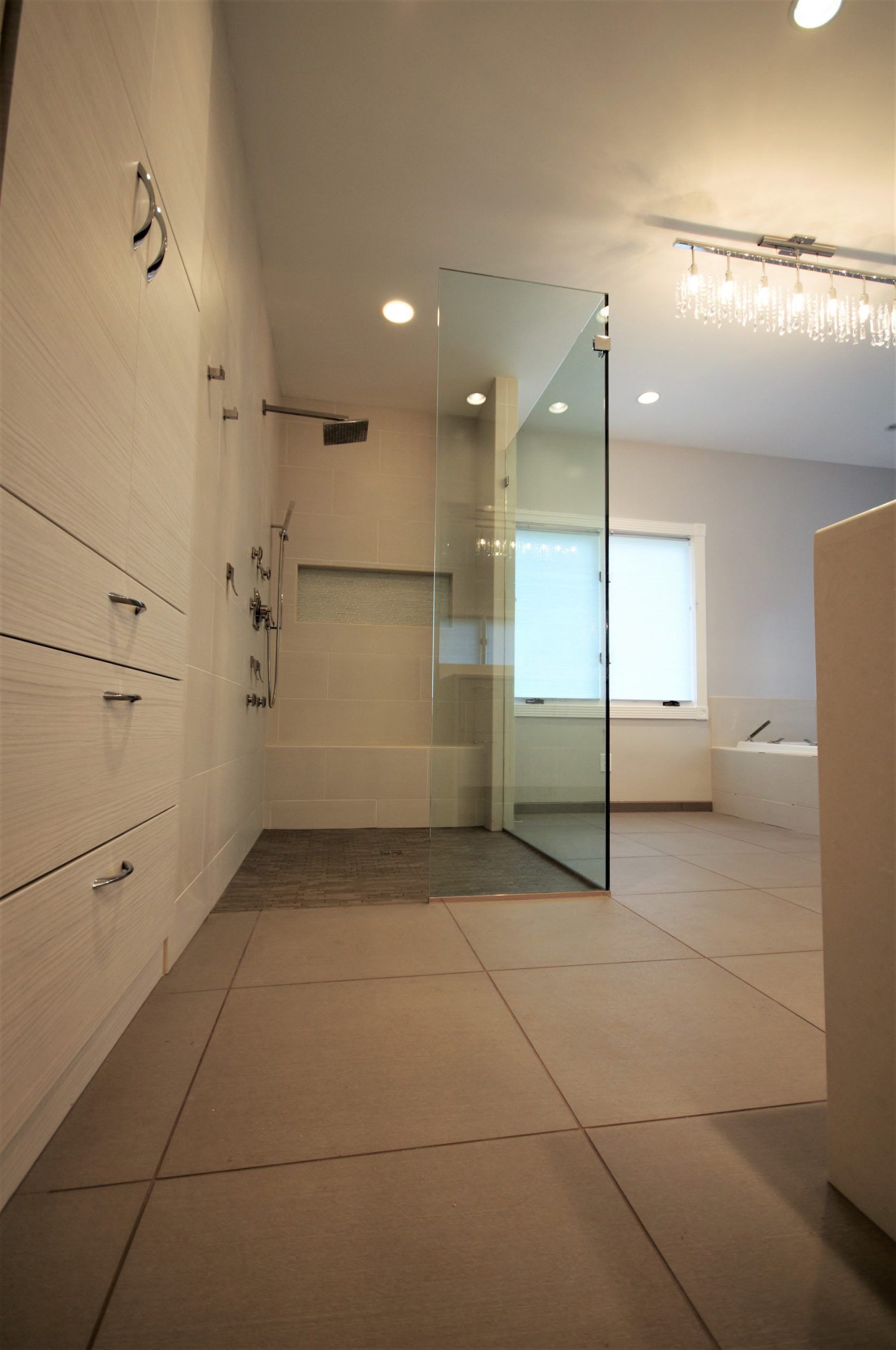 Modern bathroom with glass shower enclosure, tiled floor, and recessed ceiling lights in Montgomery Country MD