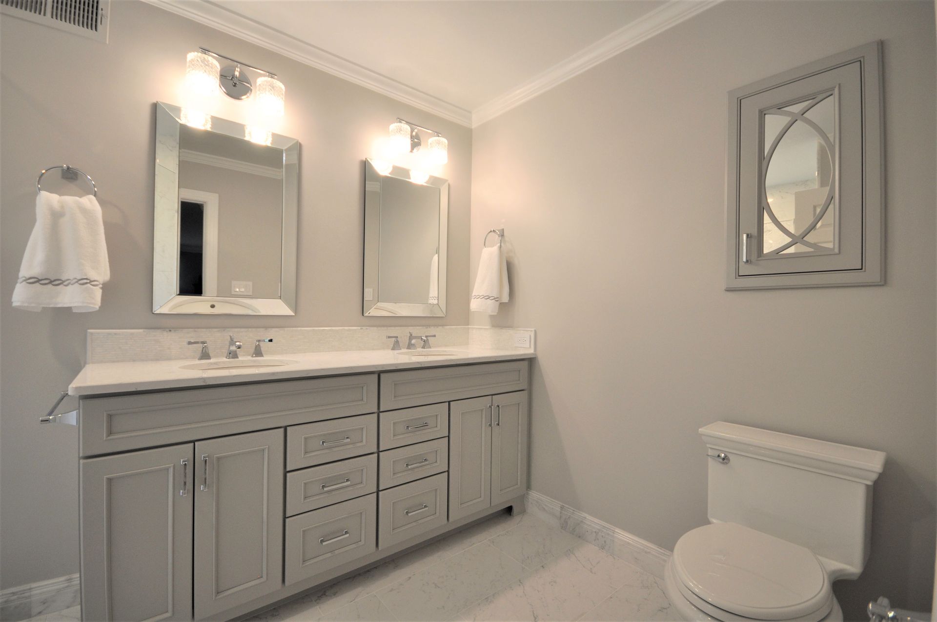 Modern bathroom with double vanity, mirrors, wall sconces, and a toilet  in Rockville