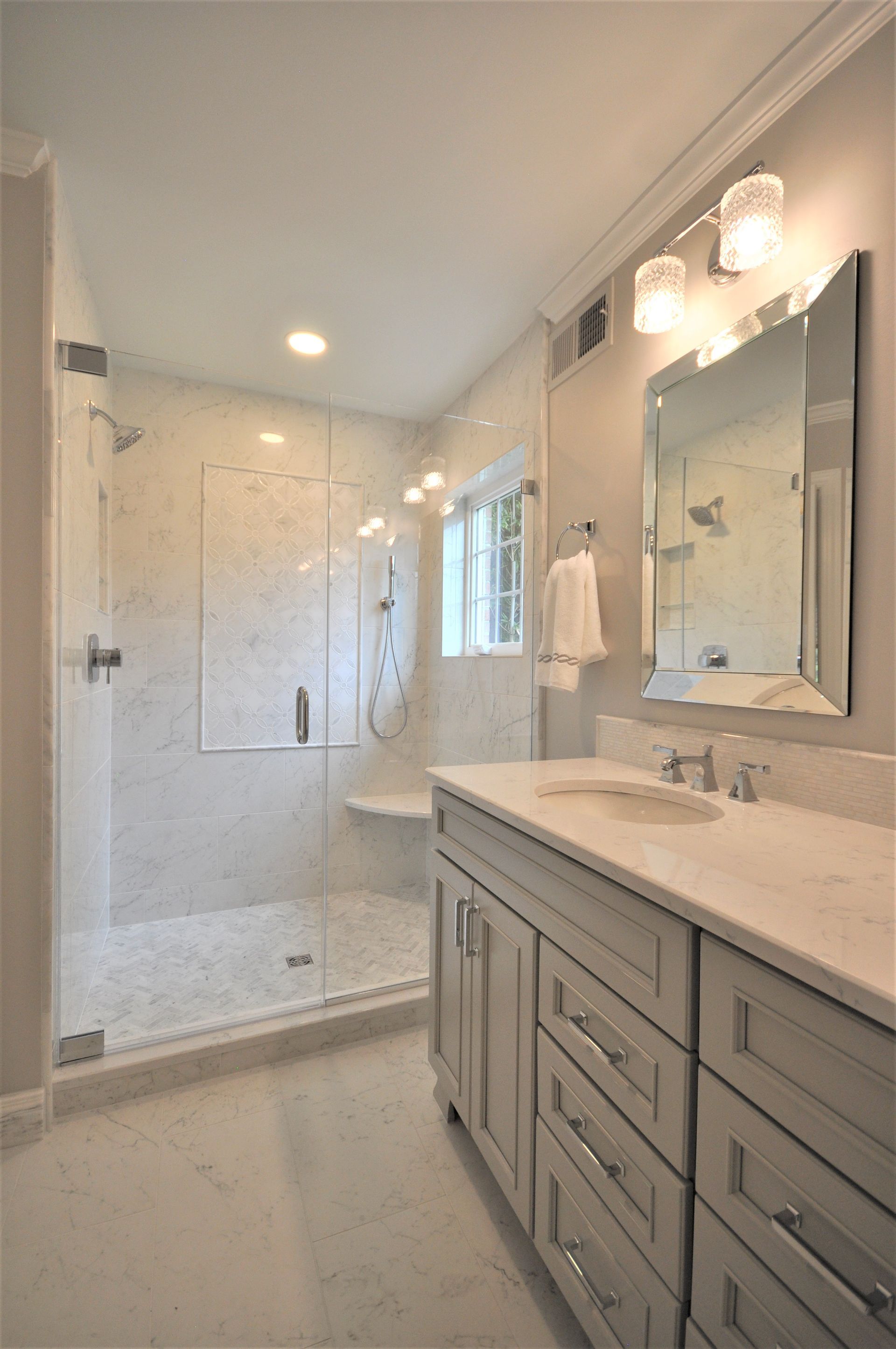 Bright modern bathroom with double vanity, large mirror, shower, and window light  in Rockville