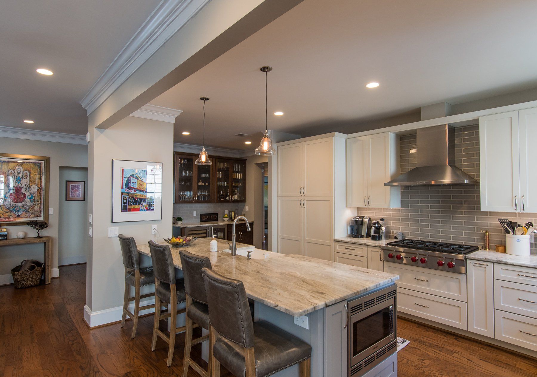 Modern kitchen with marble island, bar stools, stainless range, and hardwood floors in Rockville
