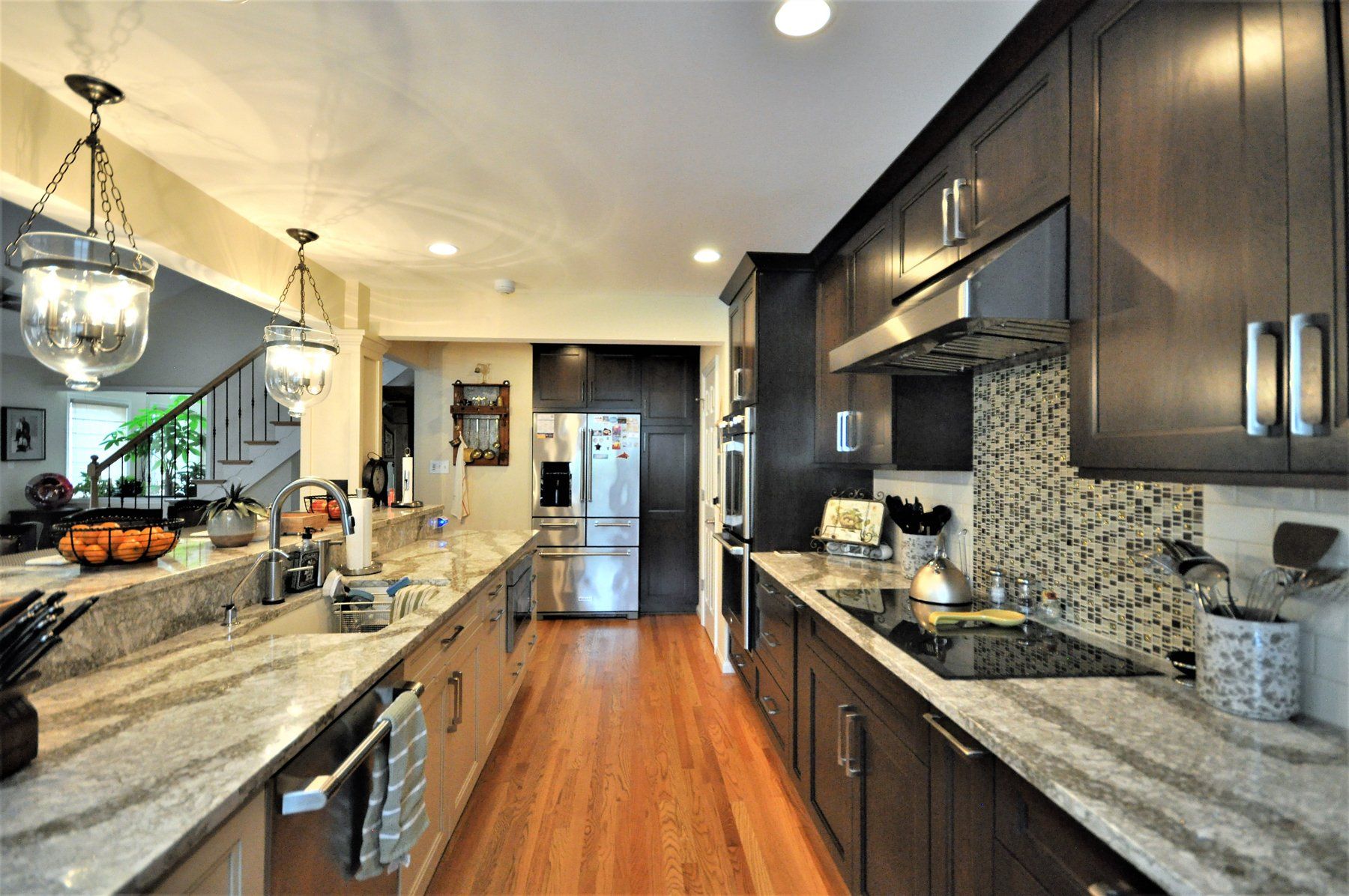Modern kitchen with dark cabinets, granite counters, stainless appliances, and warm wood floors in Rockville