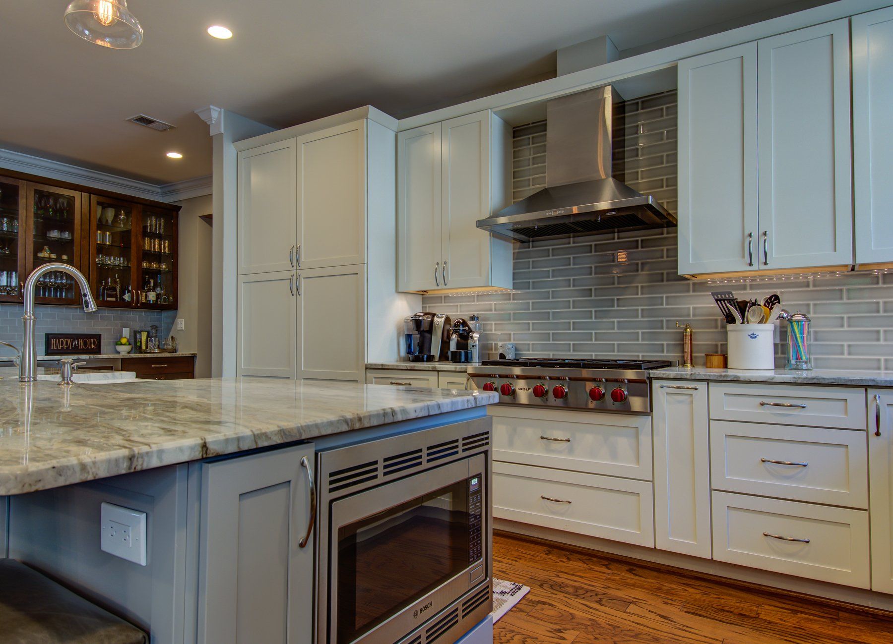 Bright modern kitchen with white cabinets, stainless appliances, gray tile backsplash, and granite island  in Rockville
