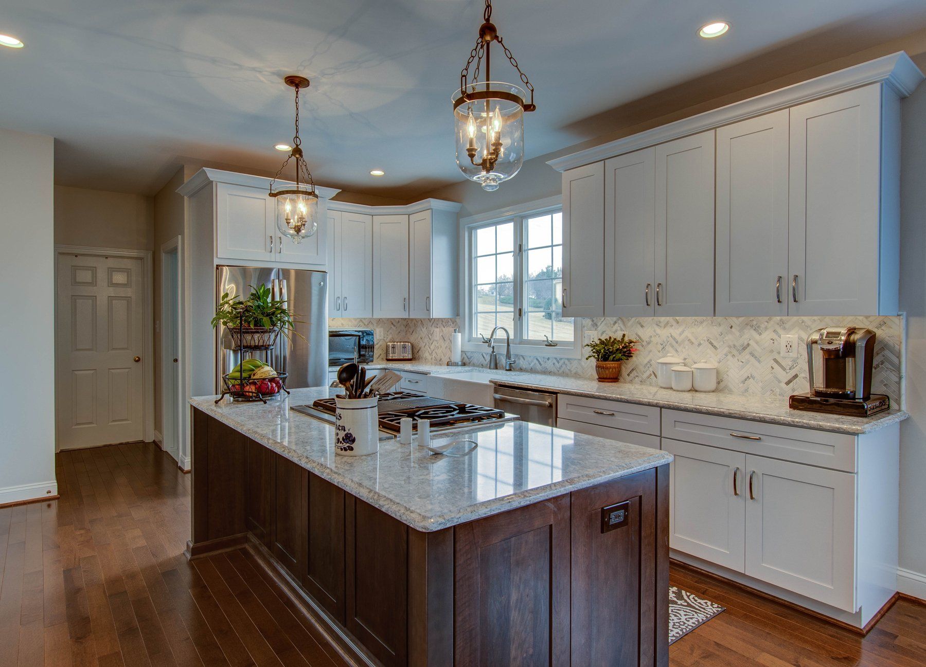 Bright modern kitchen with white cabinets, granite island, and pendant lights in Bethesda