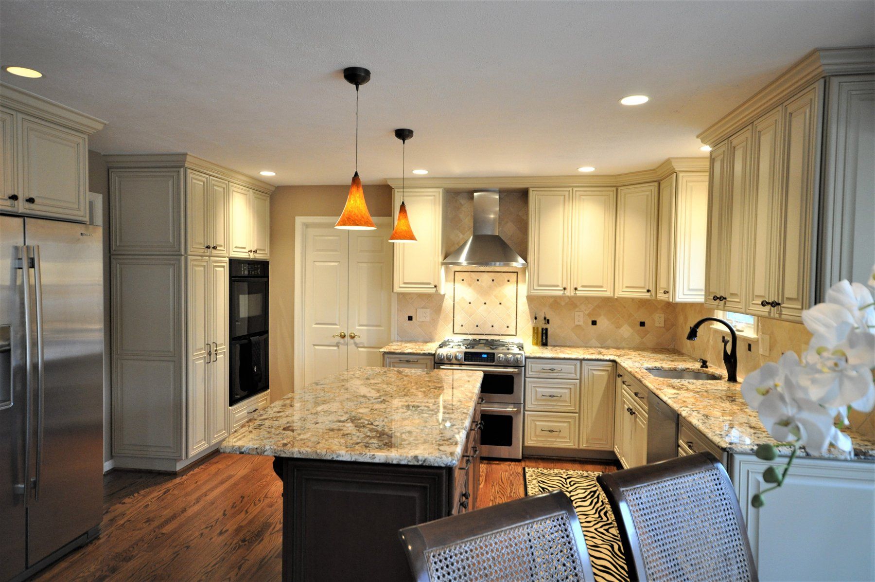 Bright modern kitchen with white cabinets, granite island, stainless appliances, and pendant lights  in Rockville