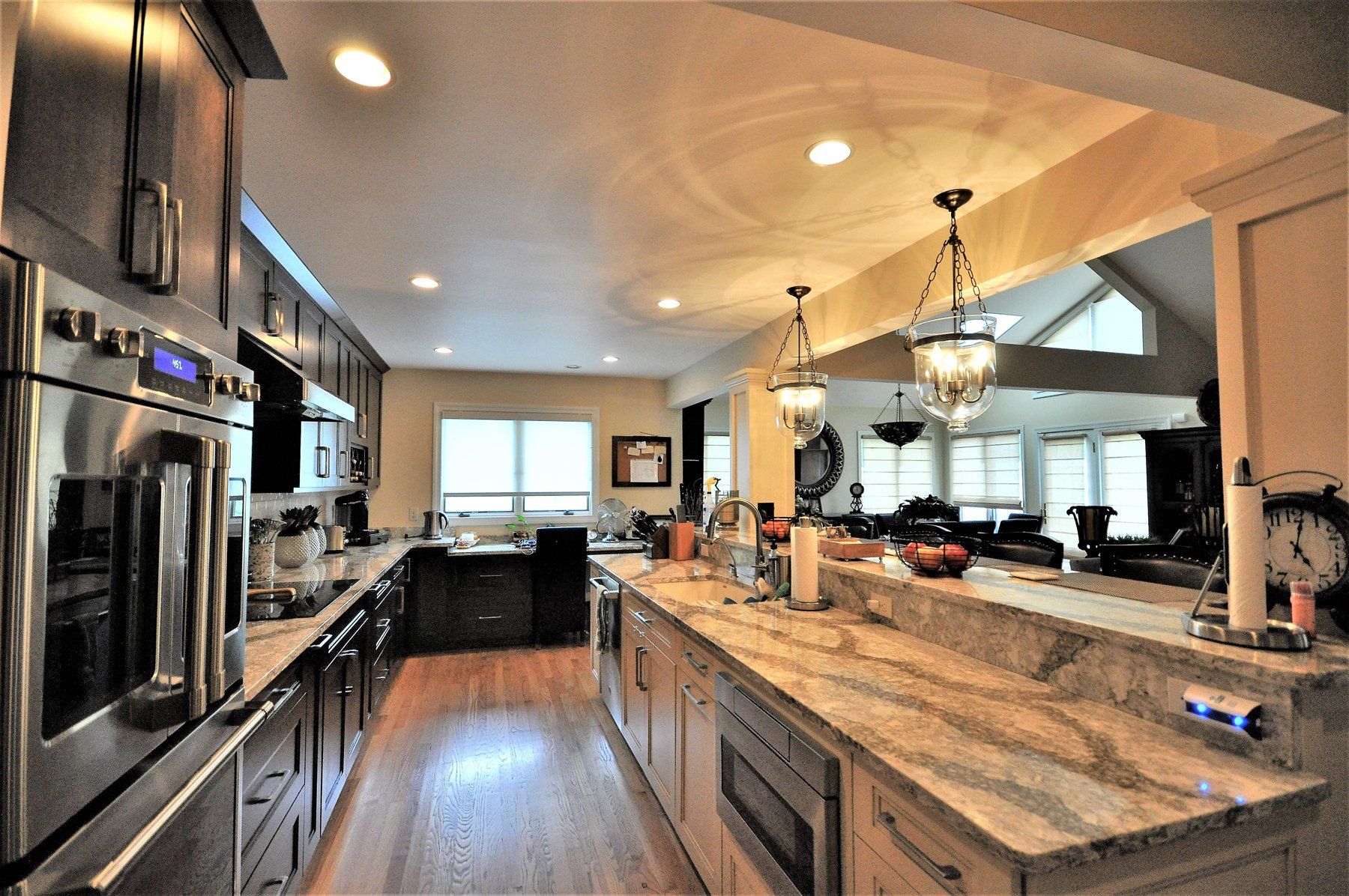 Modern kitchen with granite island, stainless steel appliances, pendant lights, and hardwood floors  in Rockville