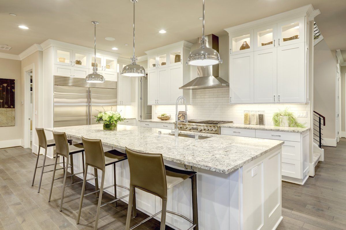 Bright white modern kitchen with large island, stainless appliances, pendant lights, and bar stools in Rockville