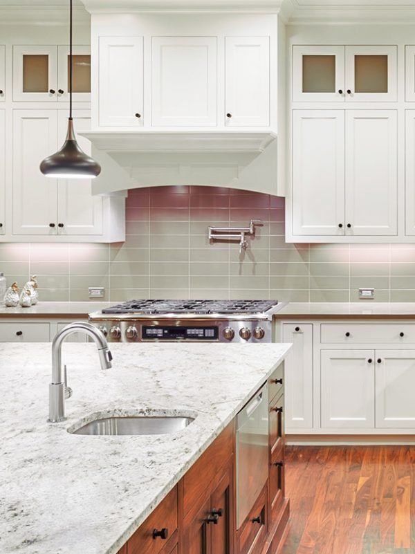 Bright white kitchen with marble island, wood floors, stainless stove, and pendant light in Olney