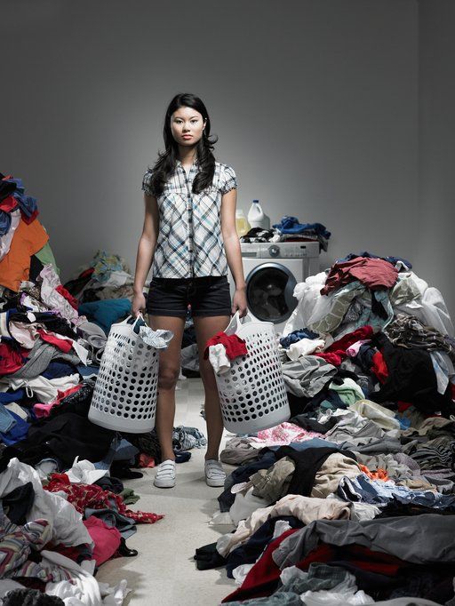Woman standing in a cluttered room surrounded by piles of clothes and laundry baskets  in Rockville