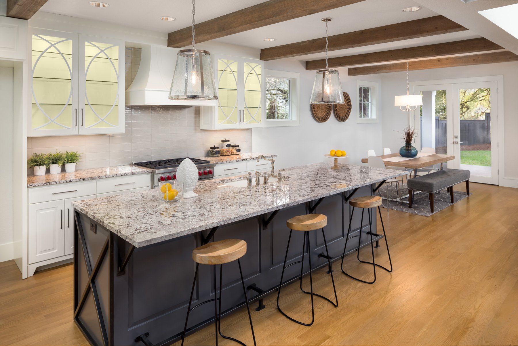 Bright modern kitchen with granite island, pendant lights, bar stools, and white cabinets