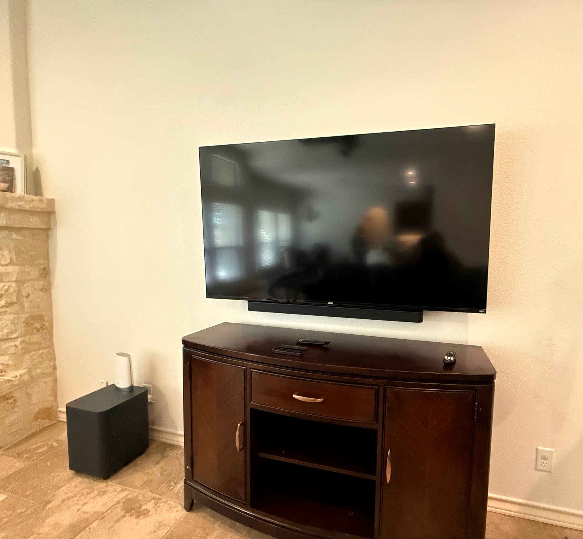 Wall-mounted TV above a dark wooden media cabinet in a beige living room