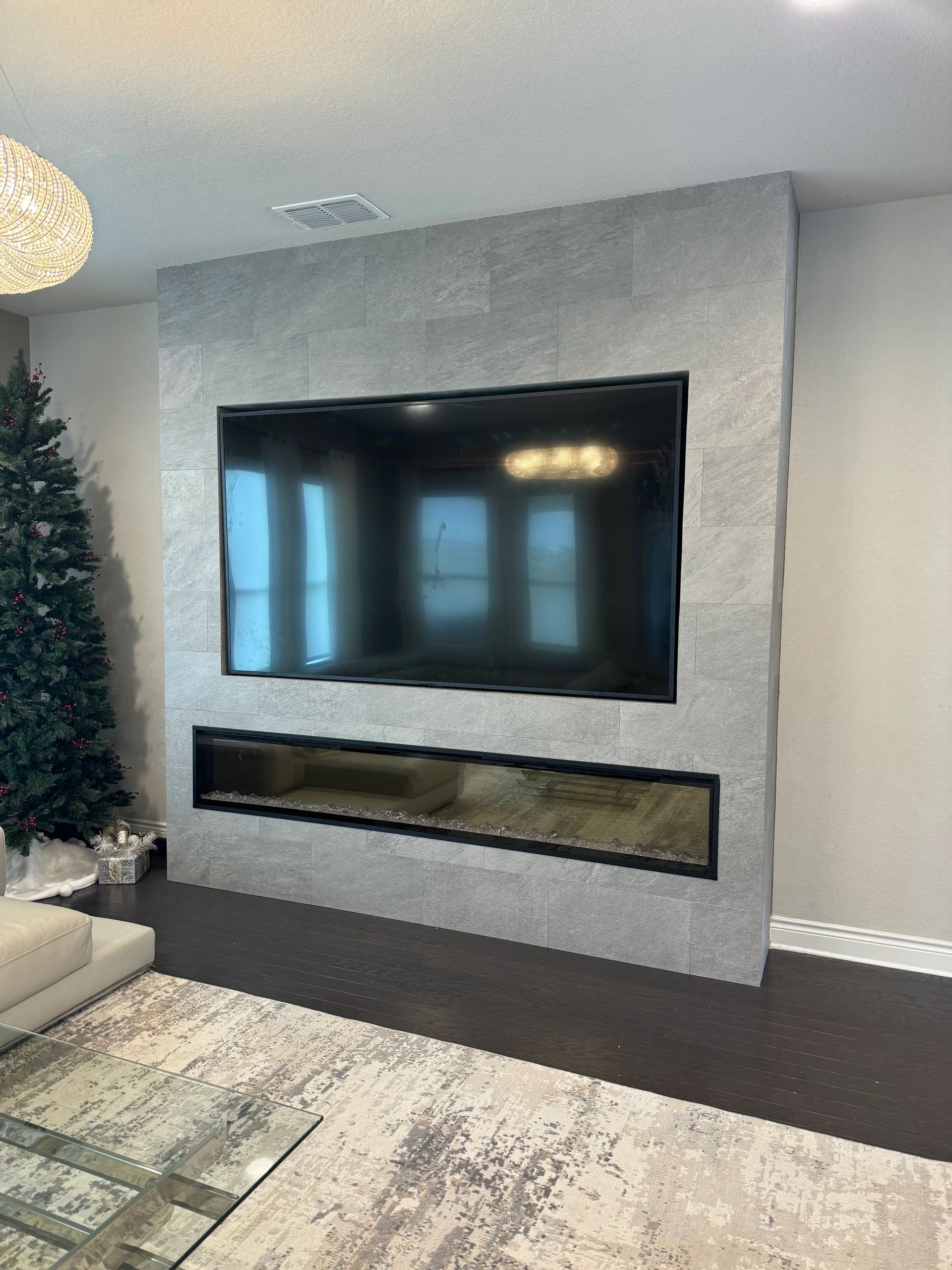 Modern living room with wall-mounted TV above a sleek linear fireplace and textured gray accent wall.