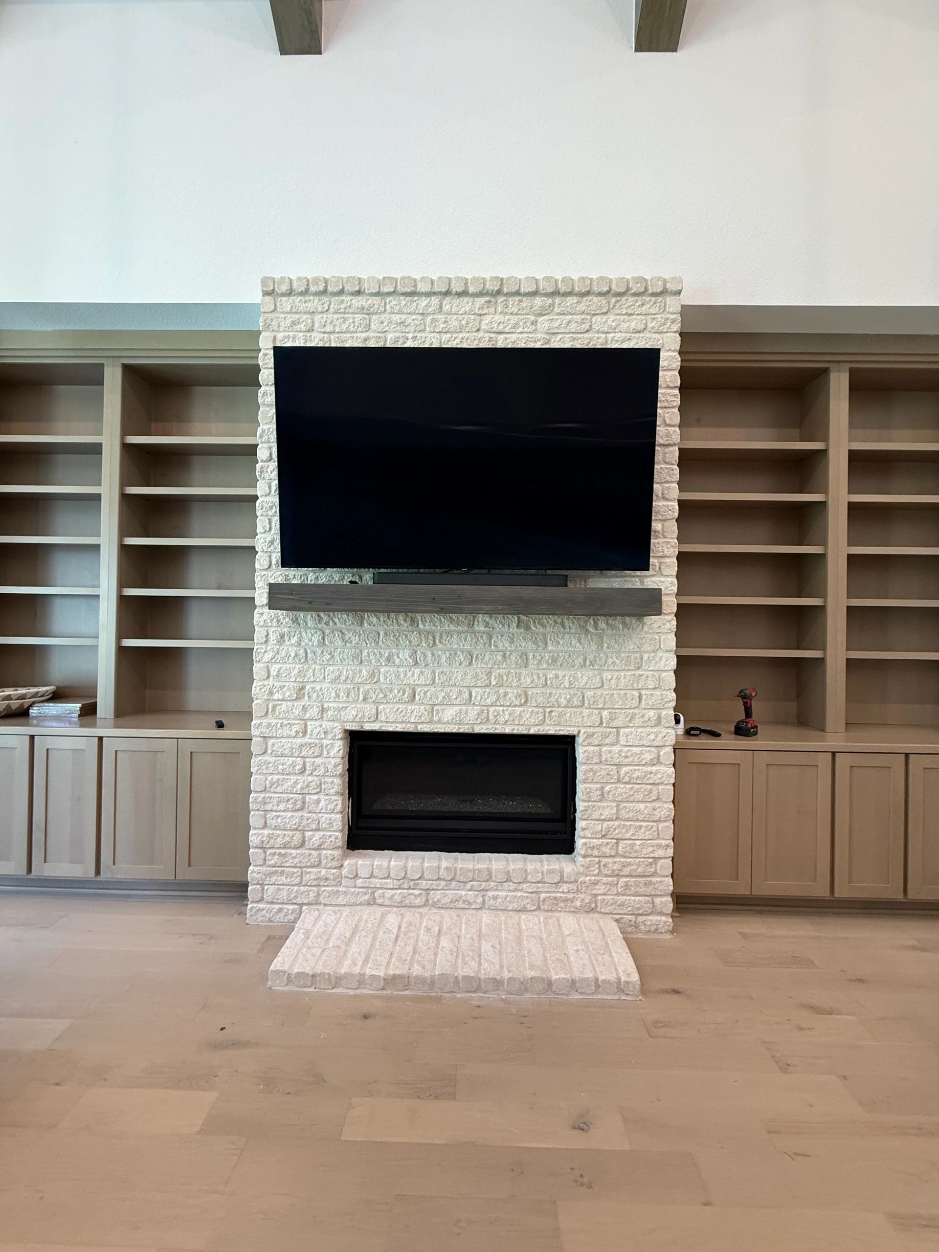 Living room wall with built-in shelves, a stone fireplace, and a large TV above it