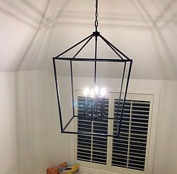 A chandelier is hanging from the ceiling in front of a window.