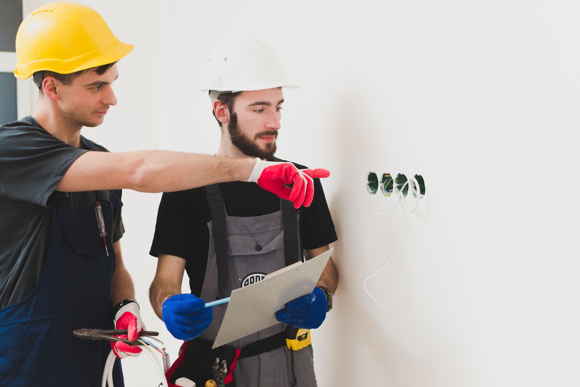 Two men are working on a wall and one is holding a clipboard.