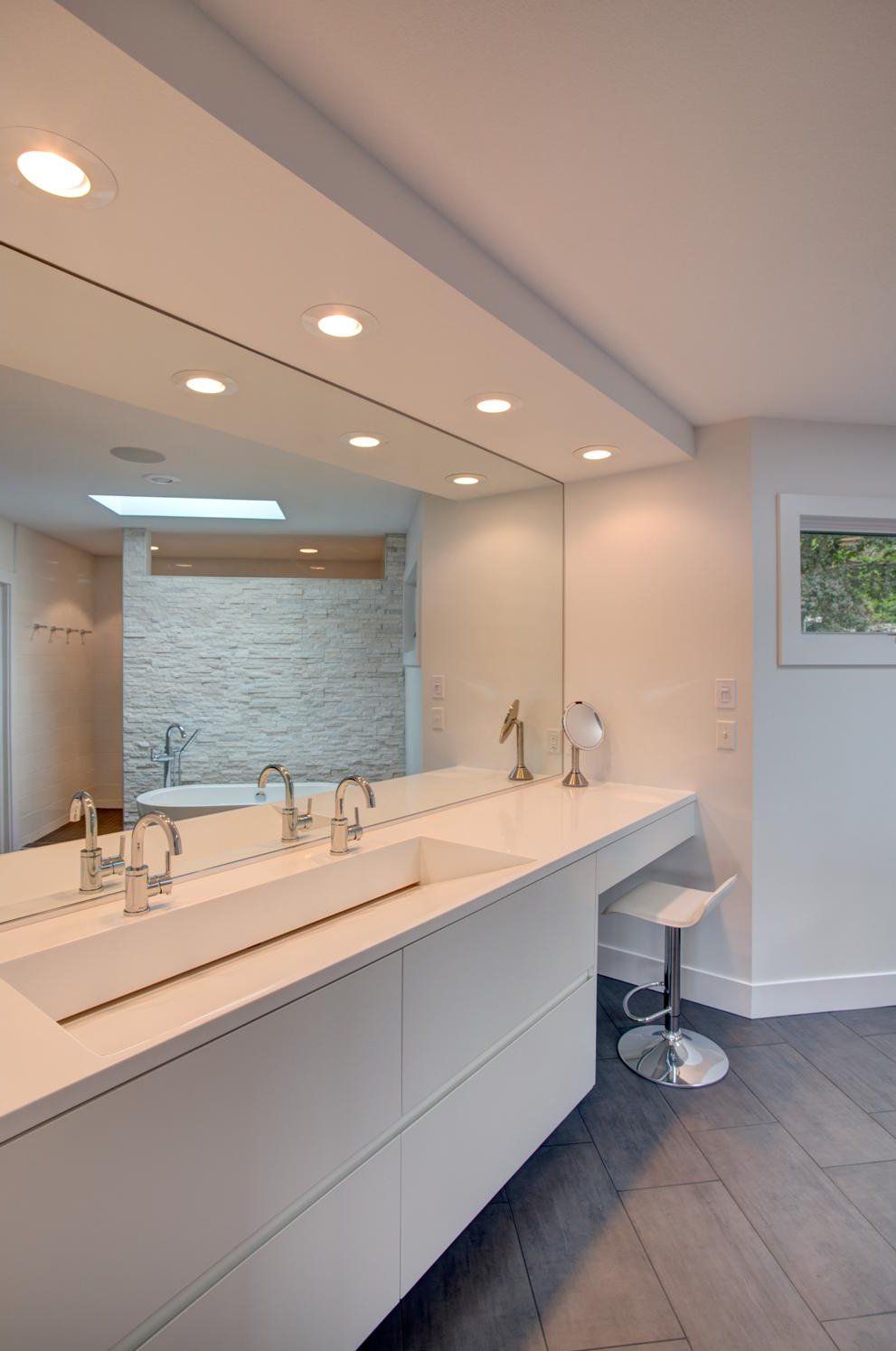 Modern bathroom with double sink vanity, large mirror, and skylight-lit stone shower wall