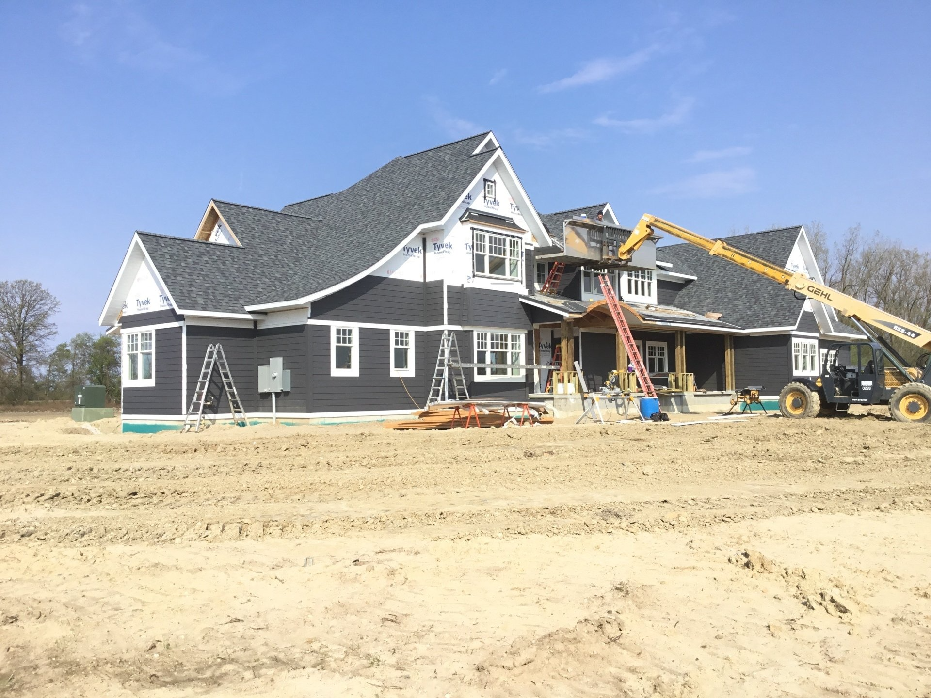A large house is being built in a dirt field.