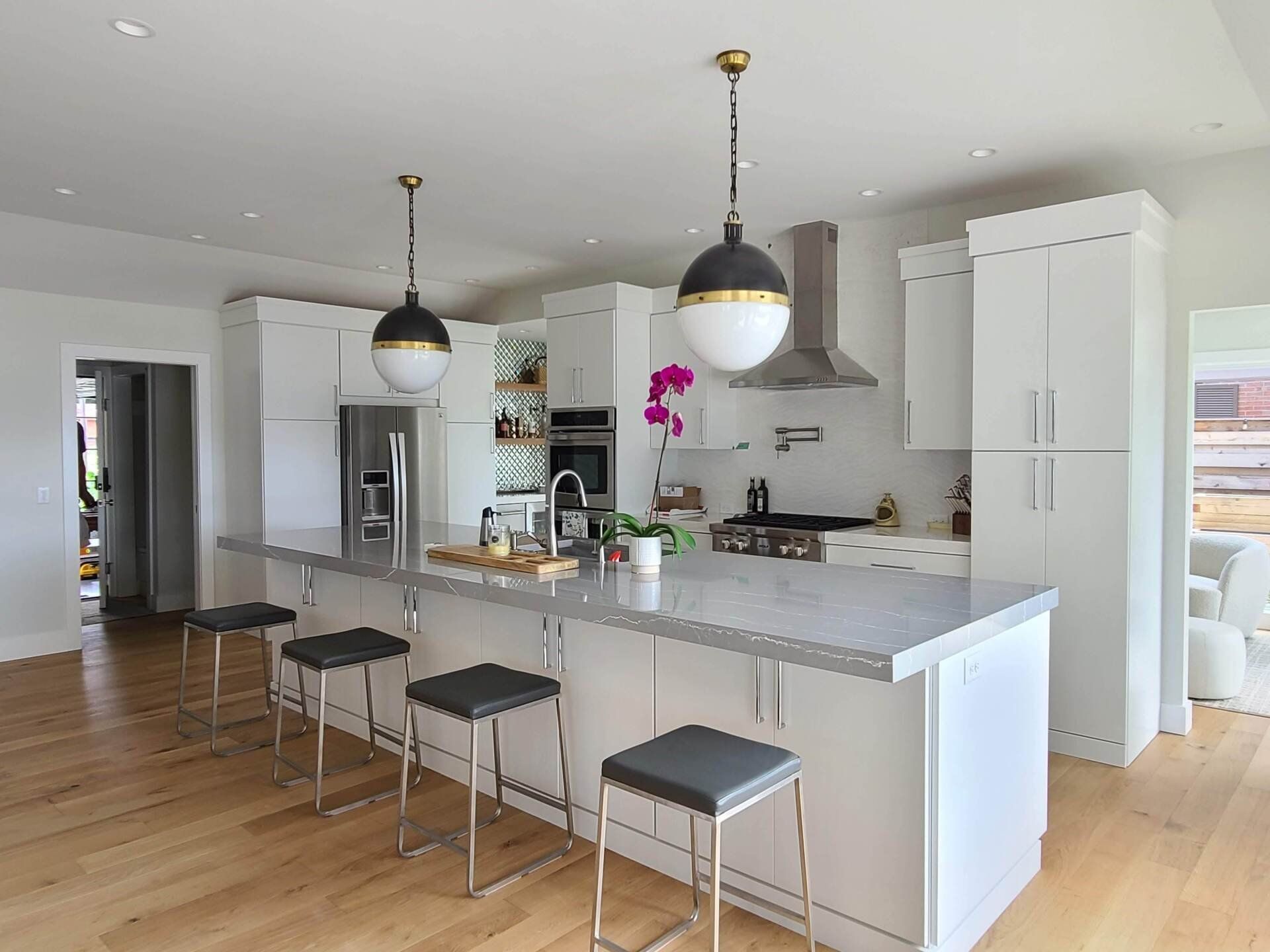A kitchen with white cabinets and stools and a large island.