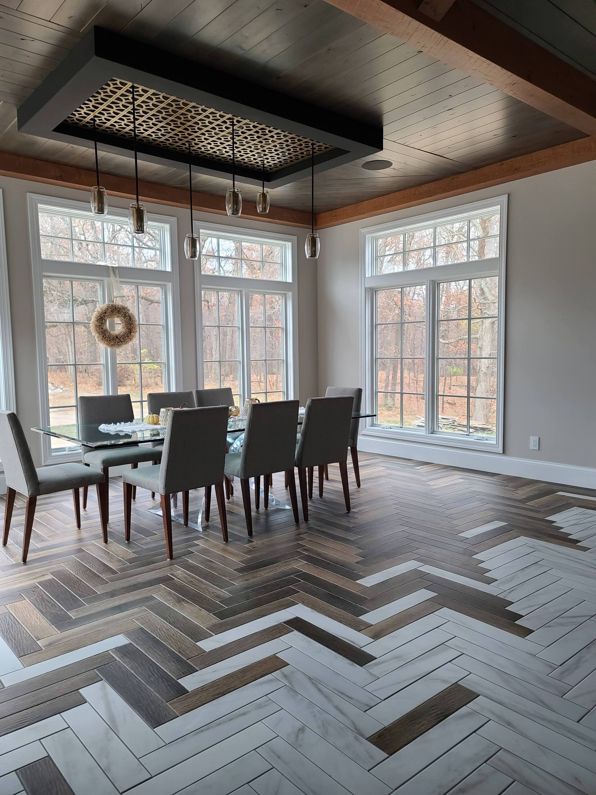 A dining room with a table and chairs and a herringbone floor