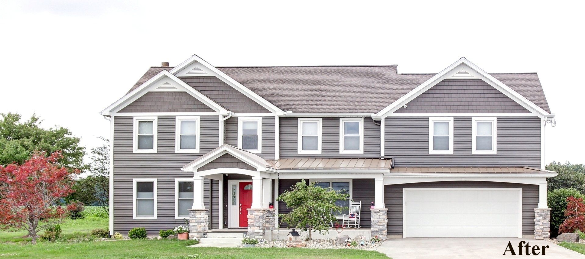 Gray two-story suburban house with white trim, red front door, and a two-car garage in front of greenery