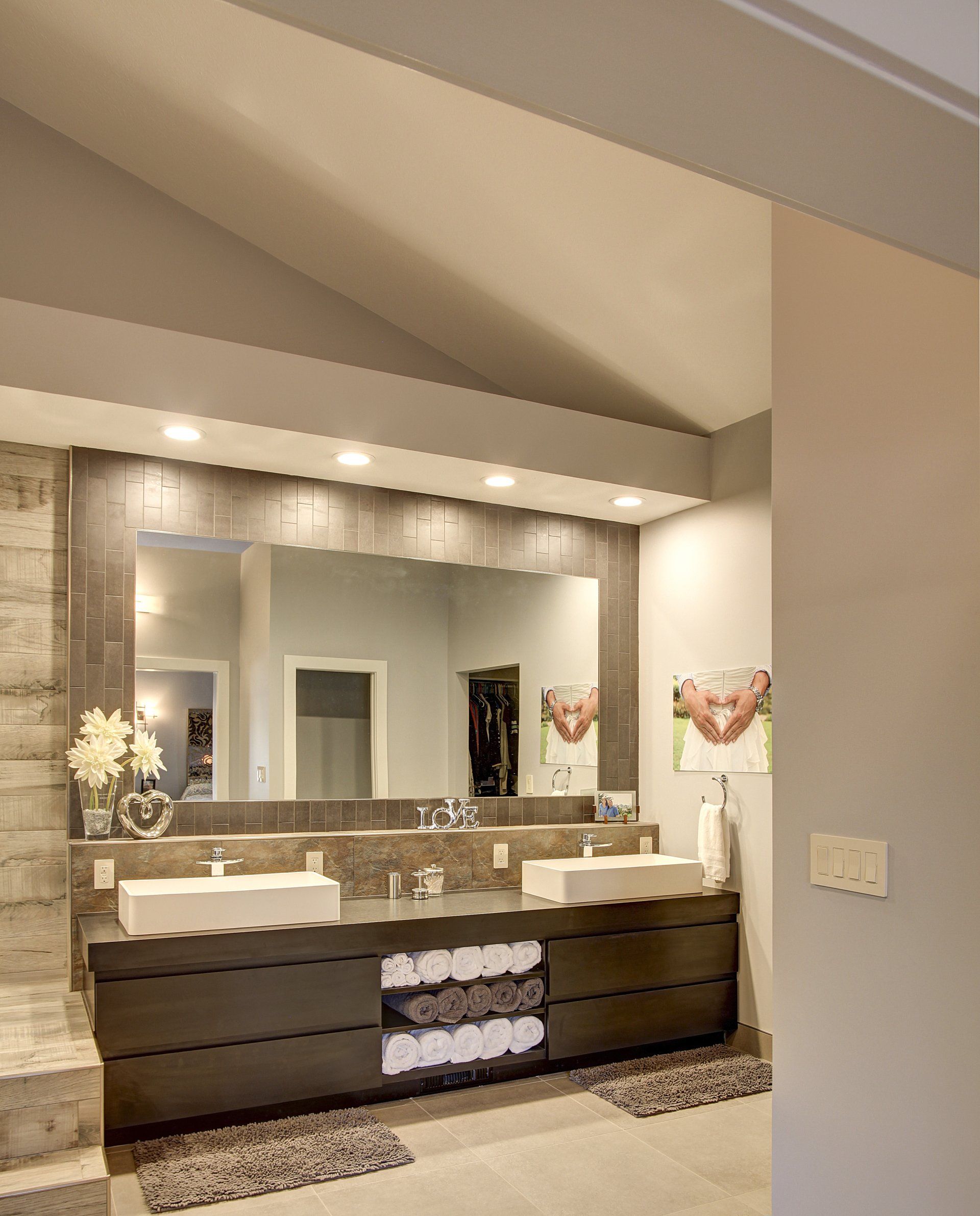 Modern bathroom with double vanity, large mirror, and neutral-toned stone finishes