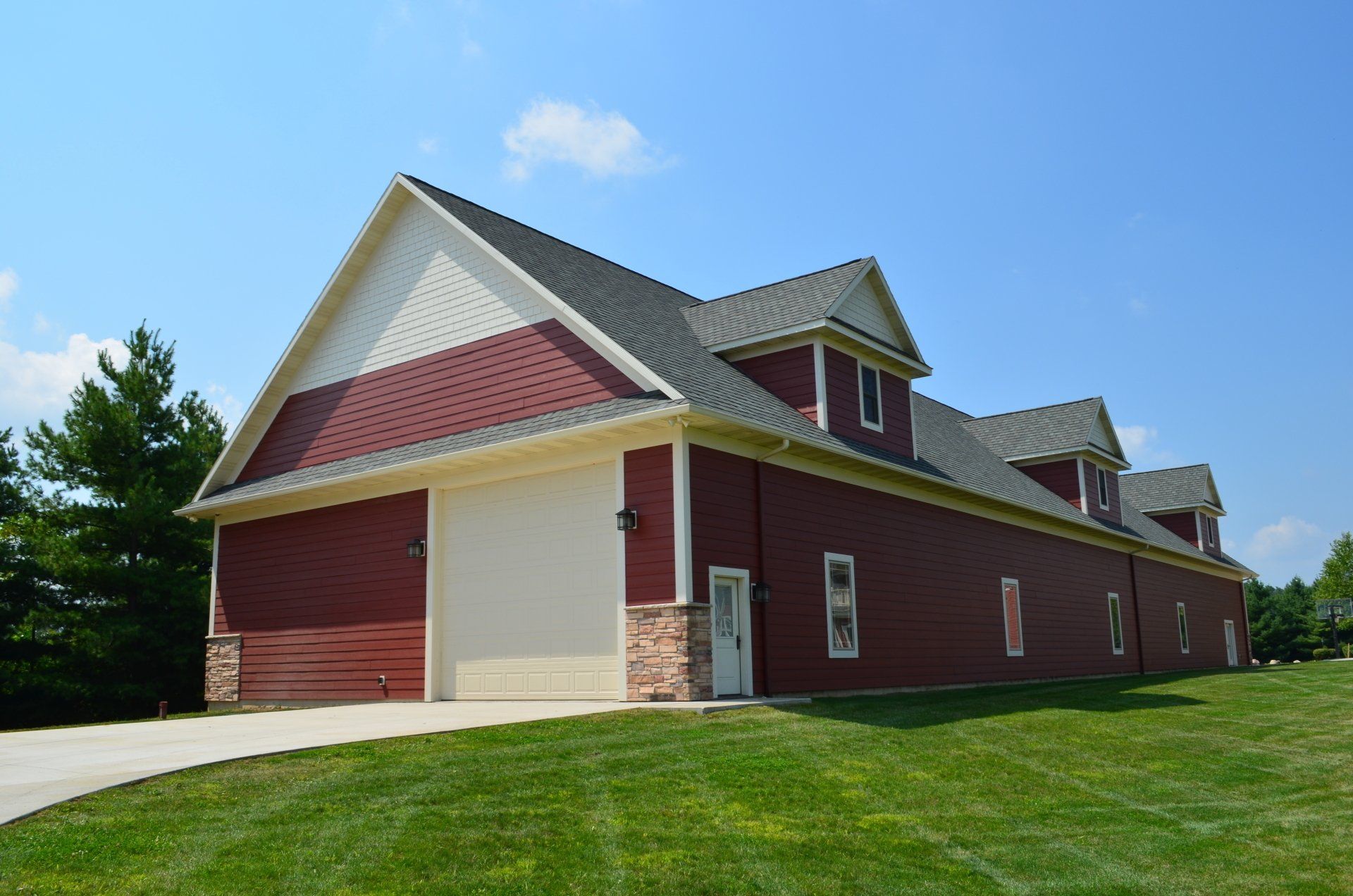 A large red and white barn with a gray roof is sitting on top of a lush green field.