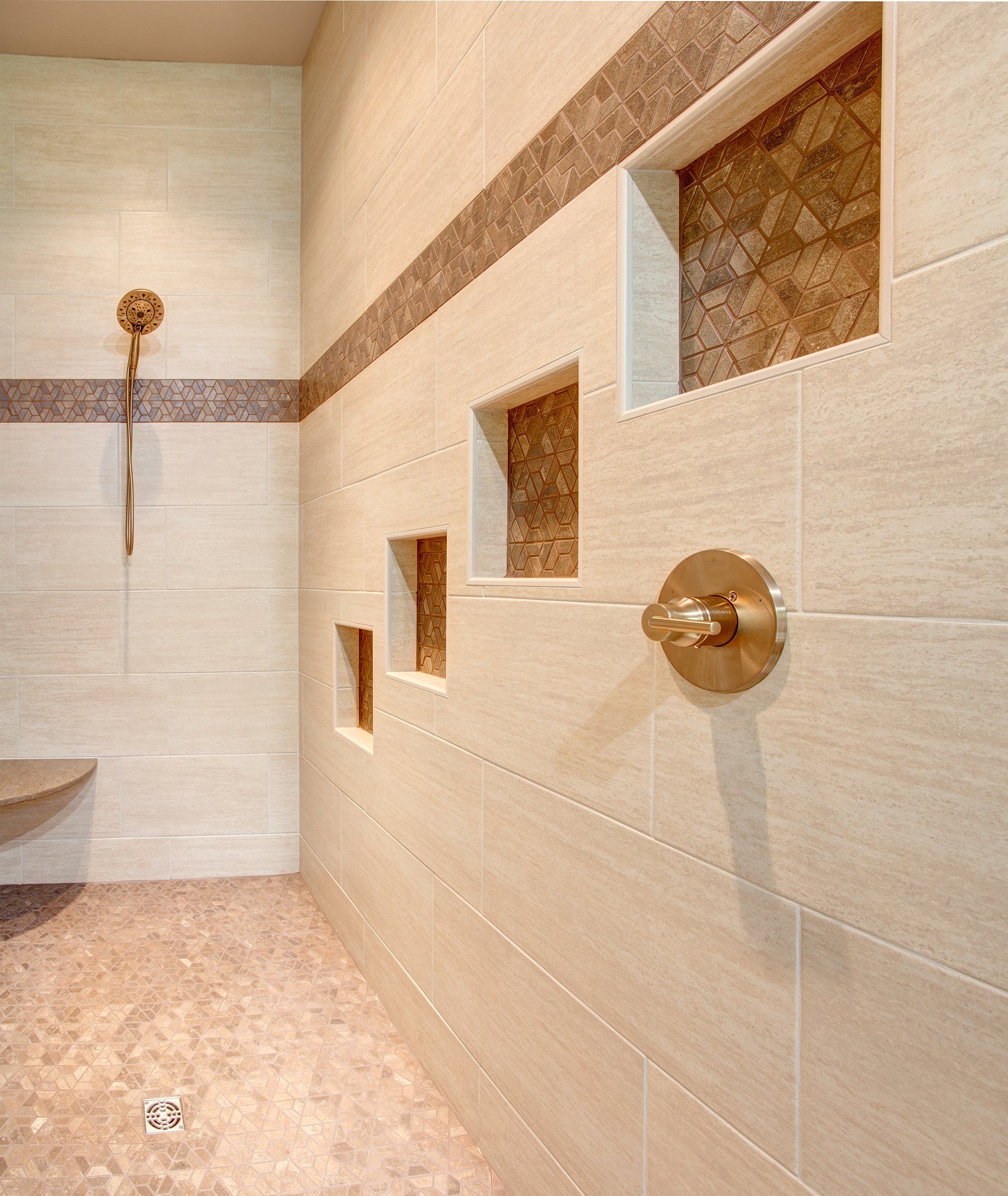 Modern tiled shower with built-in niches and brass fixtures