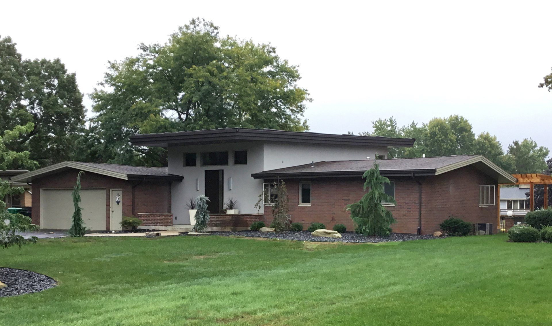 A brick house with a garage and a large lawn in front of it