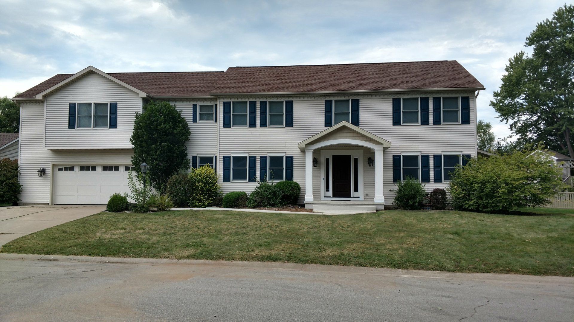 A large white house with a brown roof and black shutters