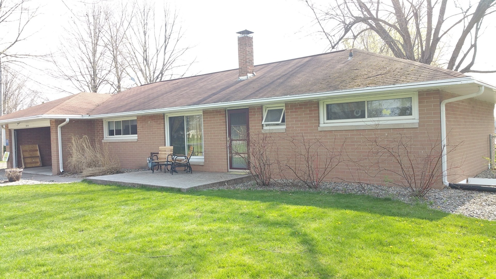 A brick house with a large lawn in front of it.