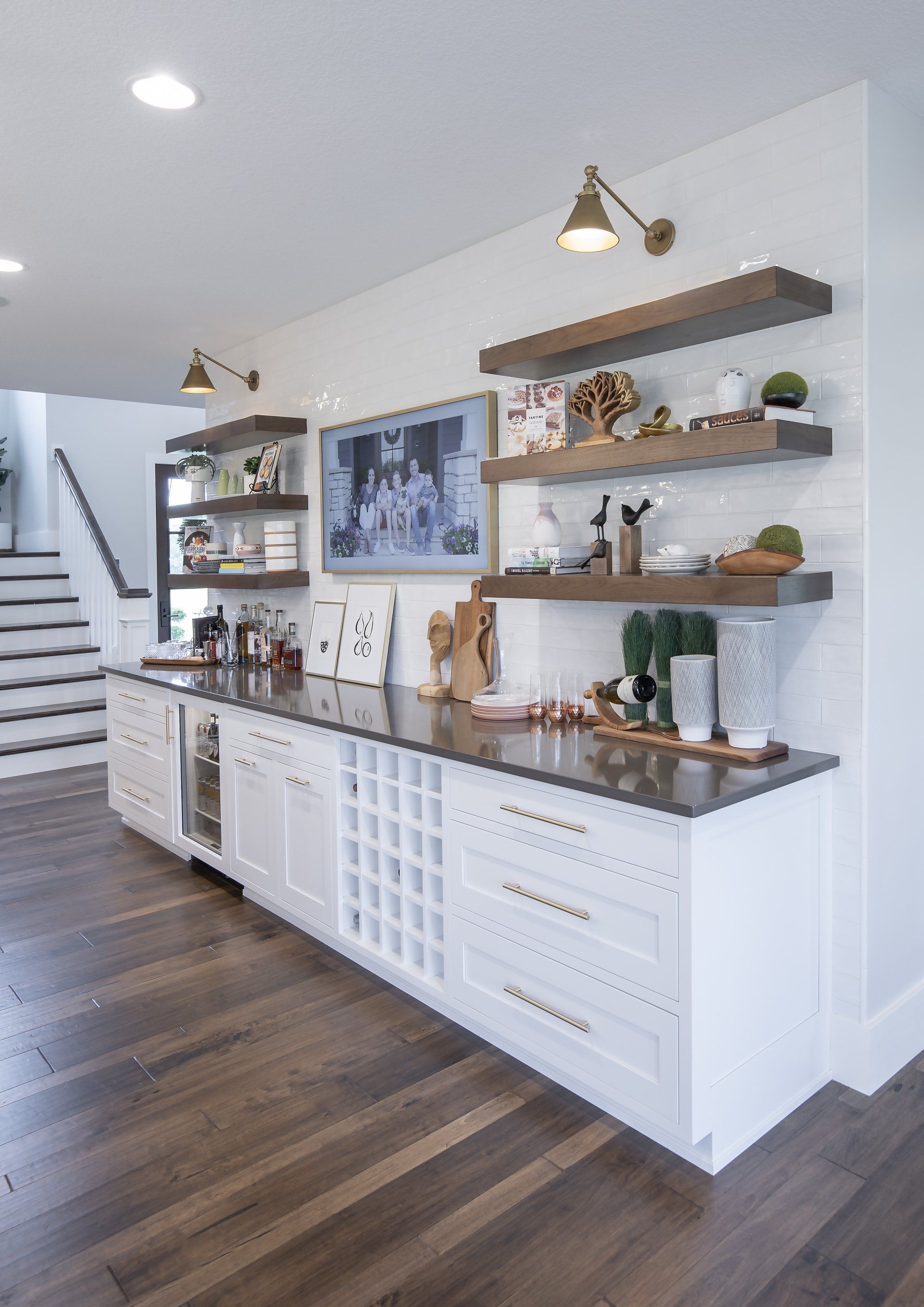 A kitchen with white cabinets and wooden floors and a wine rack.