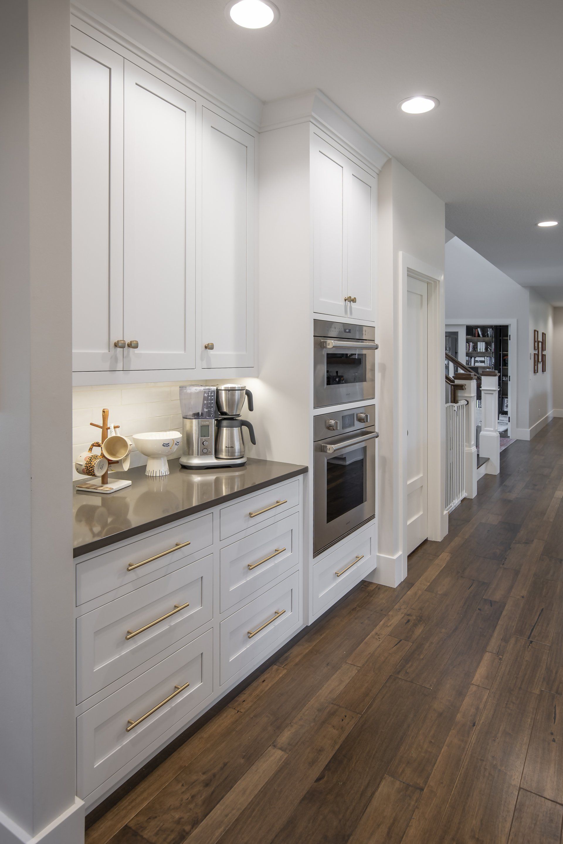 A kitchen with white cabinets , hardwood floors , and stainless steel appliances.