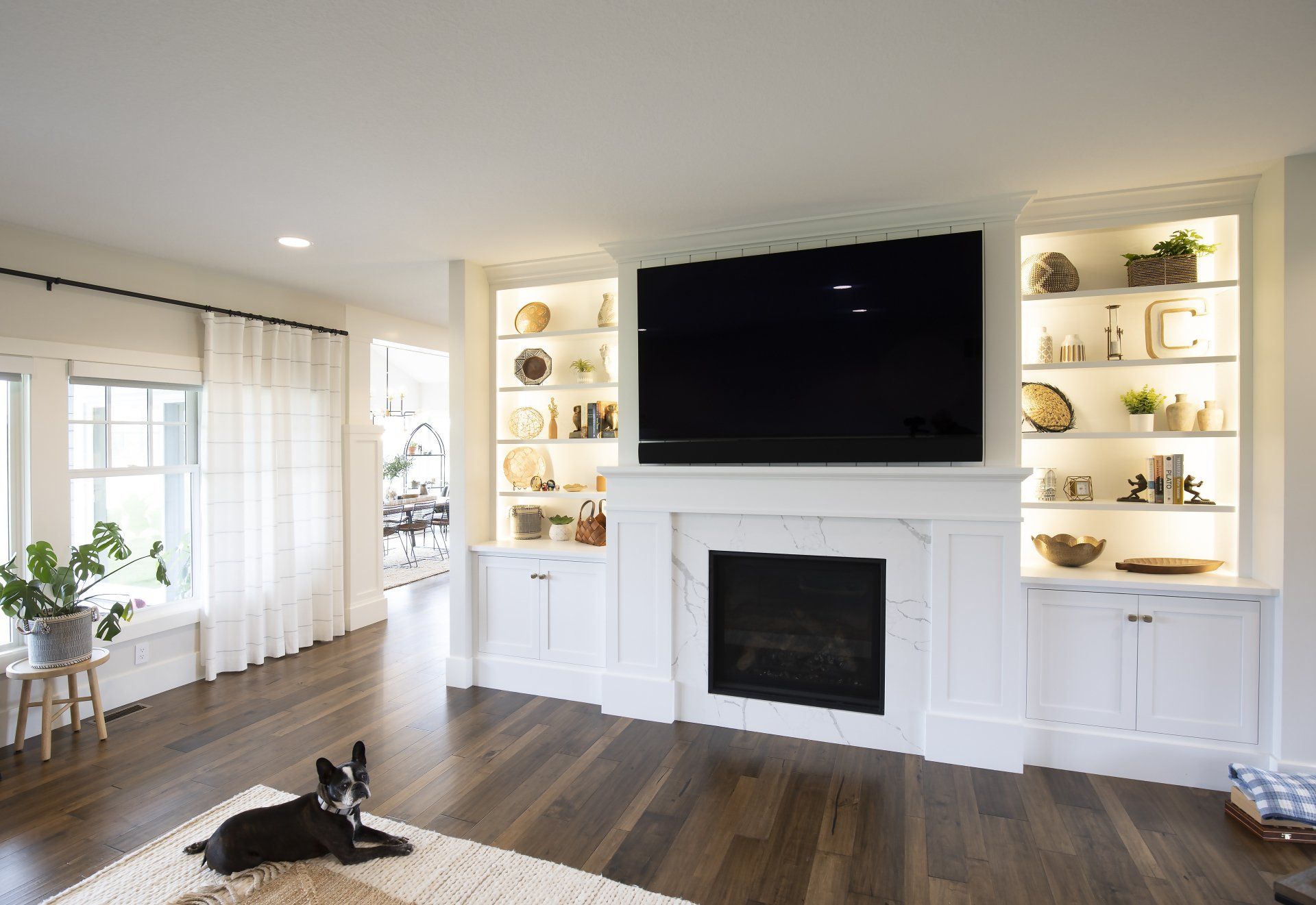 A dog is laying on a rug in front of a fireplace in a living room.