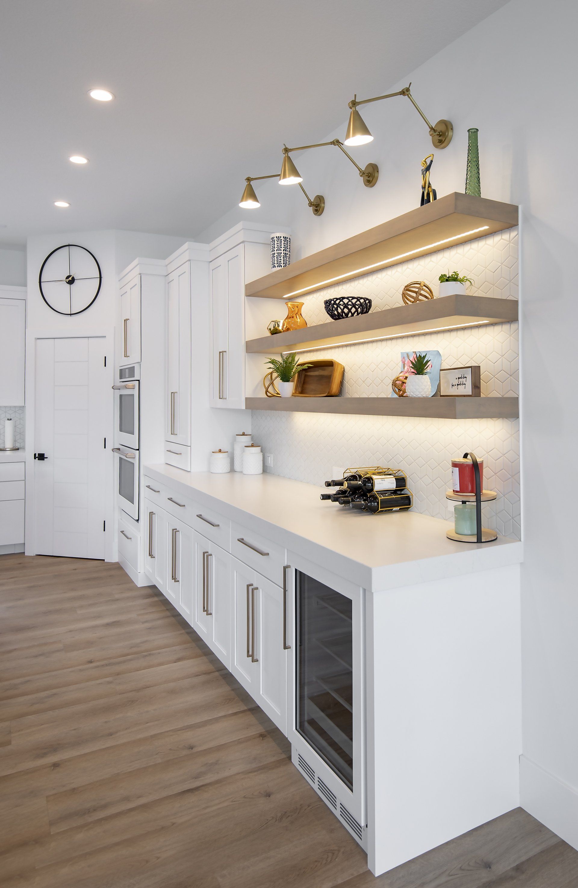 A kitchen with white cabinets , wooden floors , and a wine cooler.
