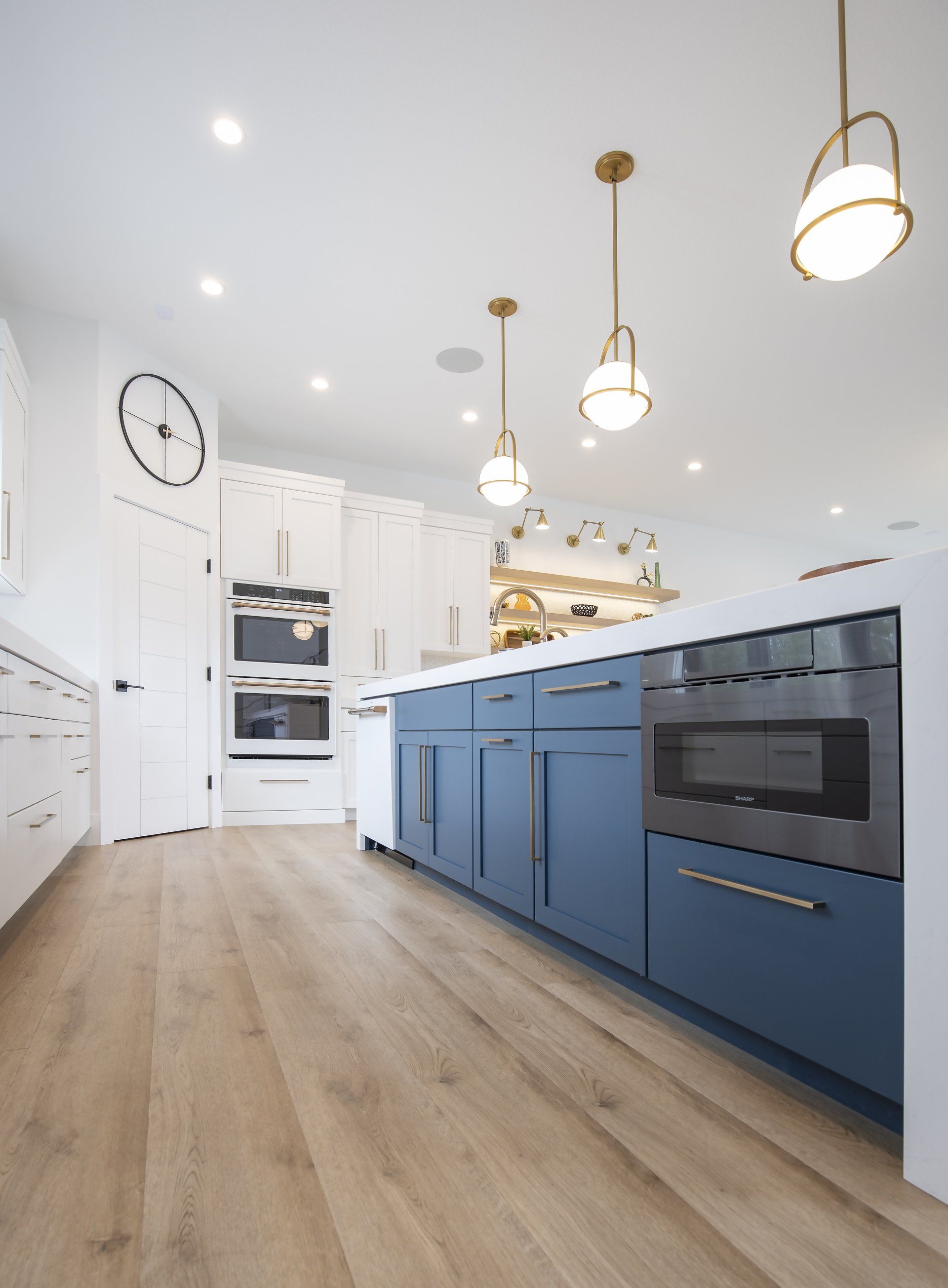 A kitchen with blue cabinets , wooden floors , stainless steel appliances and a large island.
