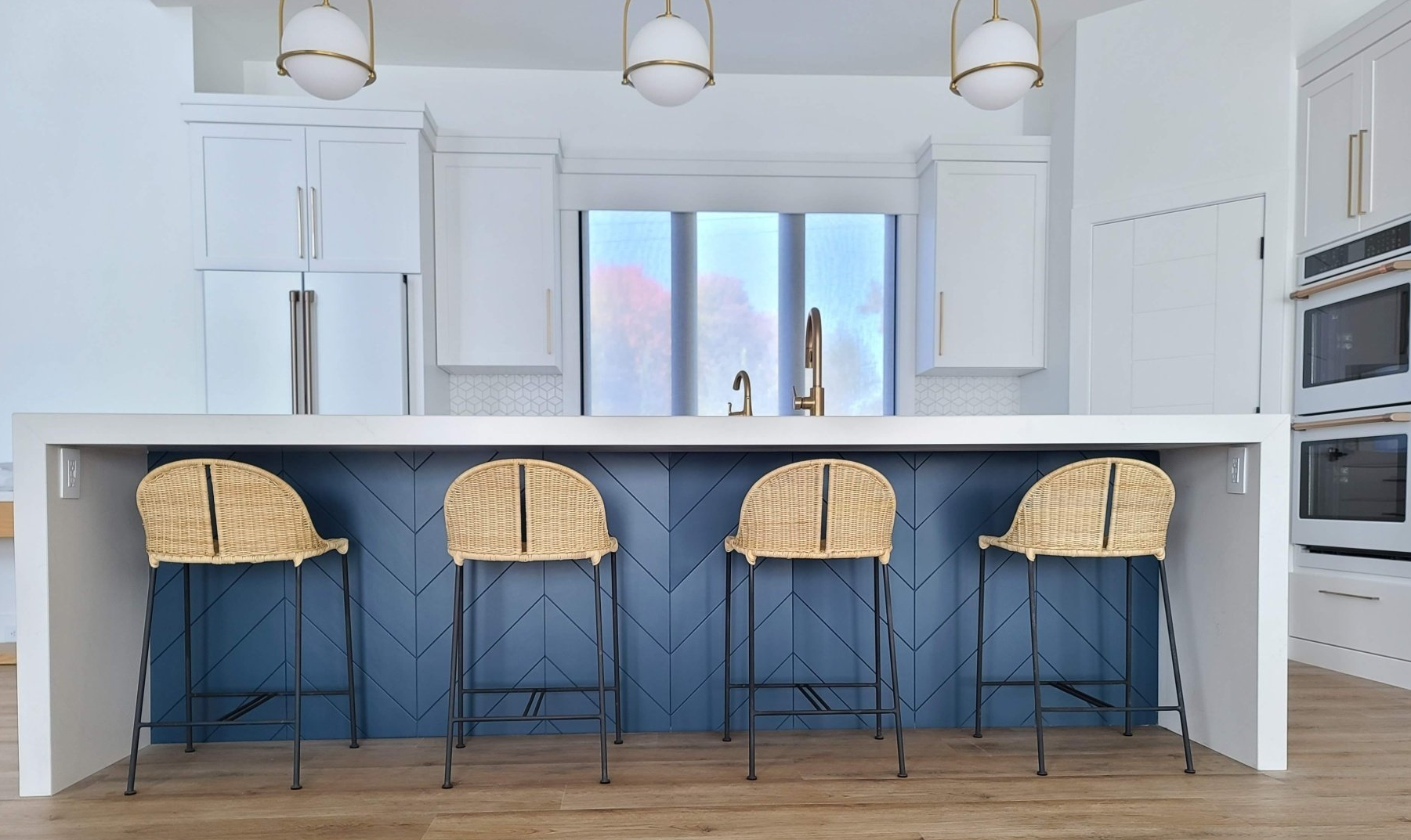 A kitchen with a large island and wicker bar stools.